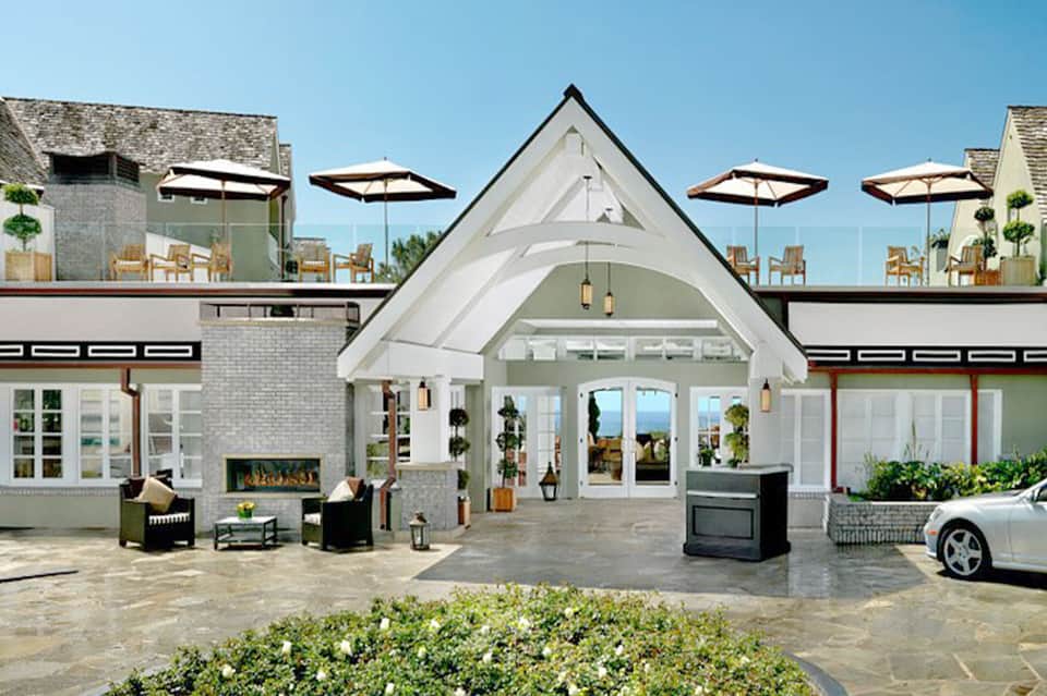 Modern resort entrance with white architectural design, umbrellas, fireplace, and ocean views