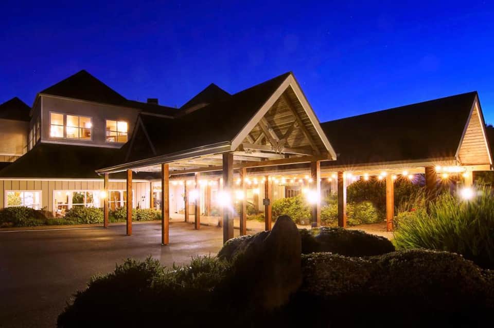 Upscale restaurant exterior lit at dusk with wooden beamed entry and large windows