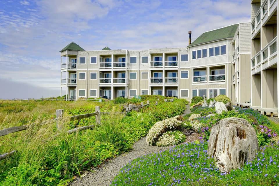 Beachfront resort buildings with green roofs and white railings overlooking coastal landscape
