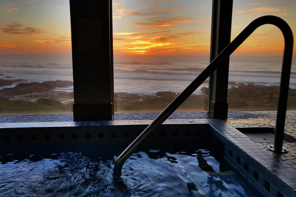 Infinity pool overlooking ocean sunset at dusk with tile details