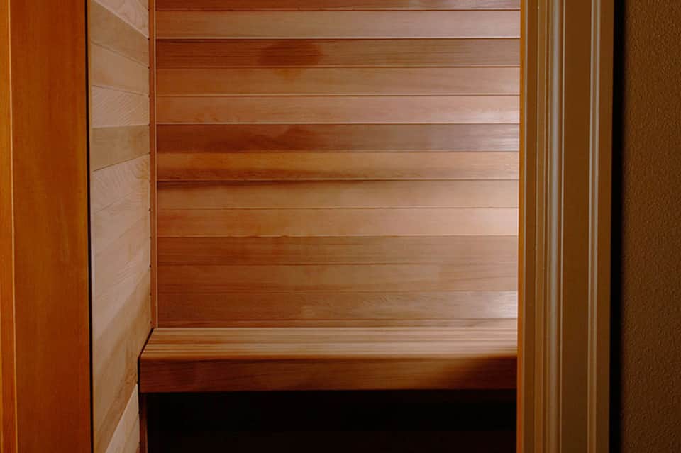 Interior wooden sauna with horizontal bench seating and natural wood paneling