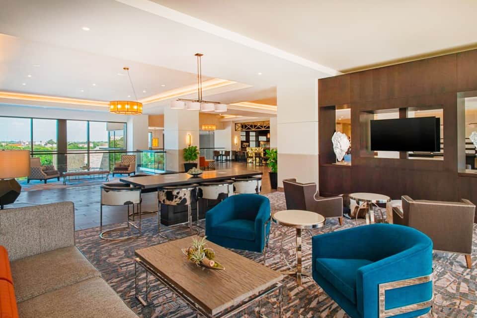 Luxury resort suite with blue armchairs, pool table, and panoramic ocean views