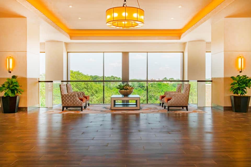Modern hotel corridor with golden lighting, floor-to-ceiling windows, and elegant furnishings