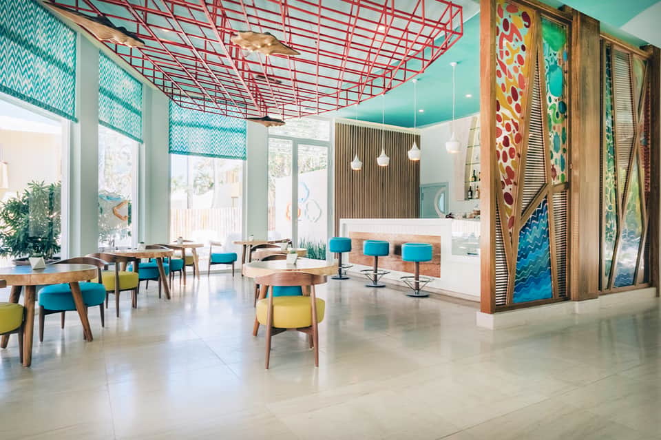 Modern resort lobby with turquoise ceiling, geometric patterns, wooden accents, and contemporary furnishings