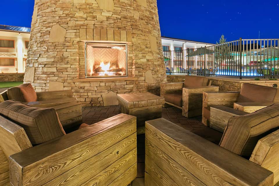 Outdoor fire pit seating area with stone fireplace and metal chairs at dusk