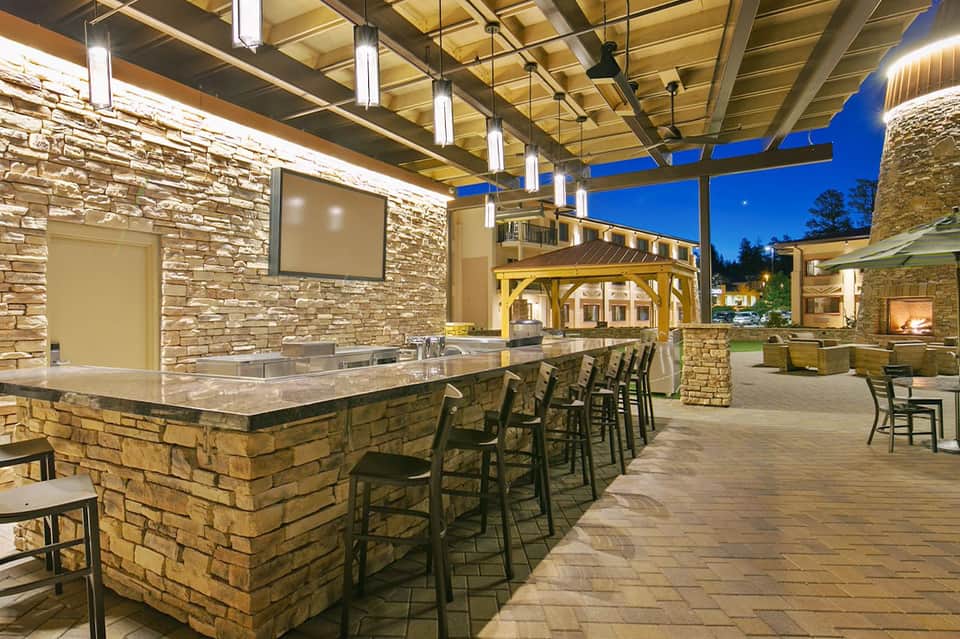 Modern outdoor kitchen and bar area with stone accents and evening lighting
