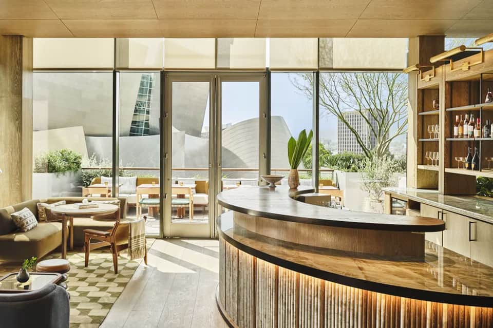 Modern spa reception area with curved wood counter, floor-to-ceiling windows, and lounge seating