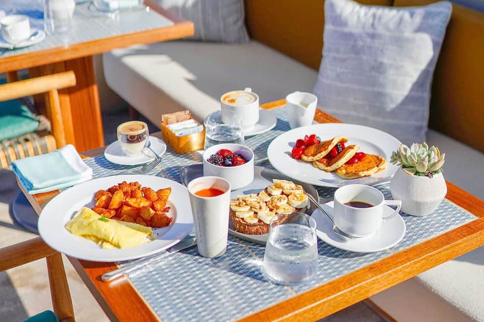 Outdoor breakfast spread with omelets, toast, berries, coffee, and fresh juice by the pool