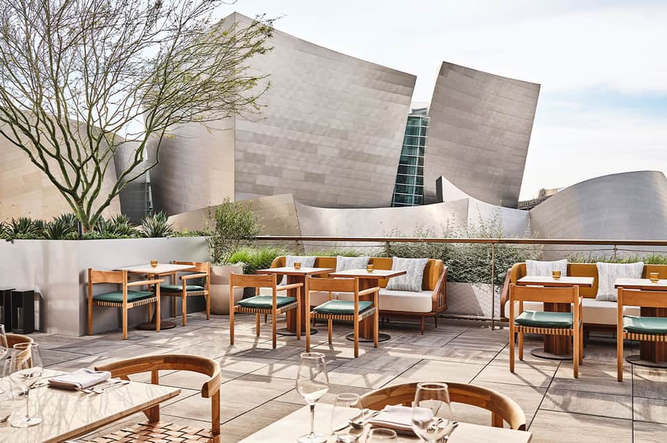Modern resort terrace with wooden furniture, white seating, and contemporary architecture backdrop