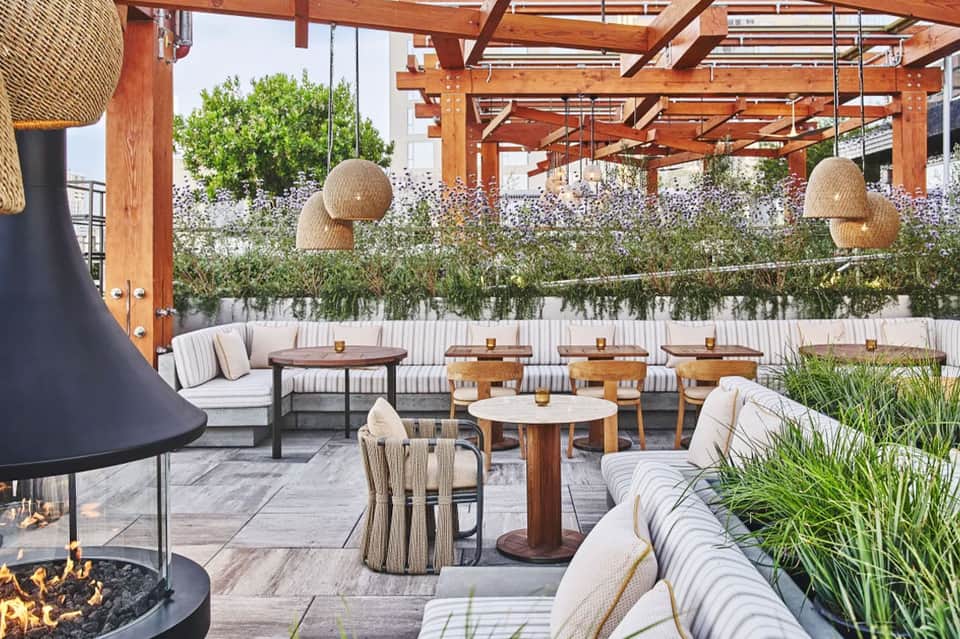 Rooftop terrace with wooden pergola, fire pit, and upholstered seating areas
