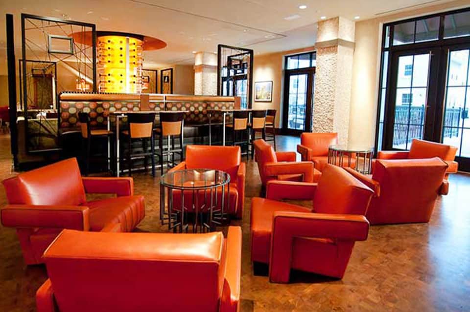 Hotel lounge with bright orange chairs, modern bar, and contemporary artwork