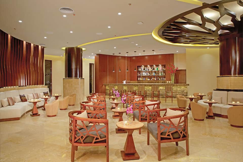 Elegant resort bar and lounge with warm lighting, decorative ceiling, and full bar