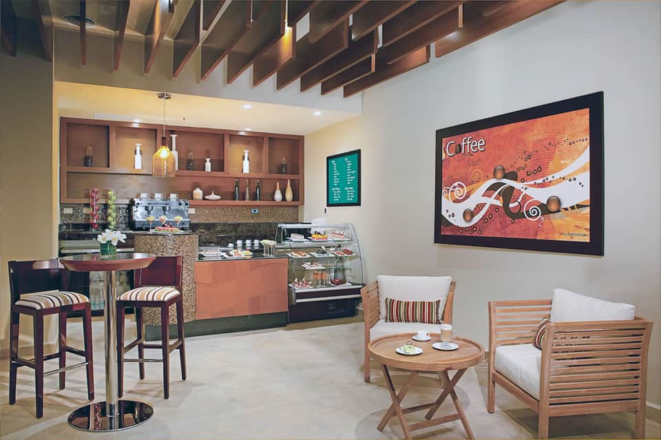 Coffee shop interior with bar seating, espresso machine, and artistic wall decor