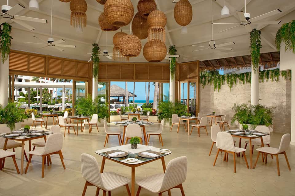 Beachfront restaurant with woven pendant lights, wooden furnishings, and ocean view