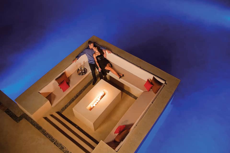 Couple in modern bedroom suite with fireplace viewed from above aerial perspective