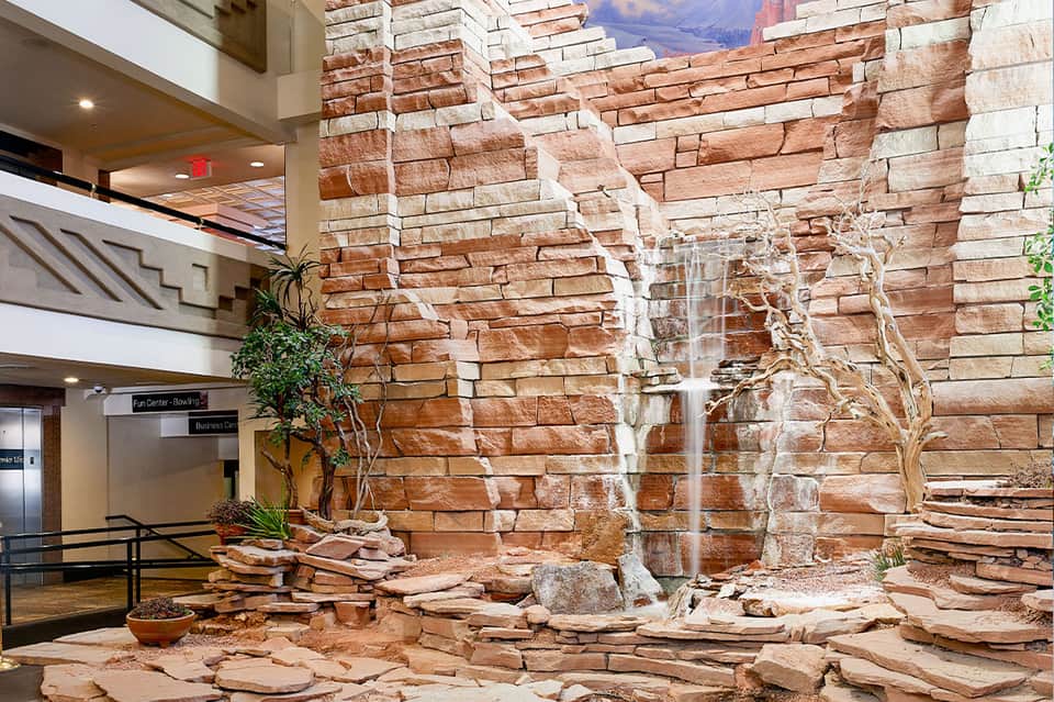 Indoor atrium with massive red stone wall, waterfall feature, and modern architecture