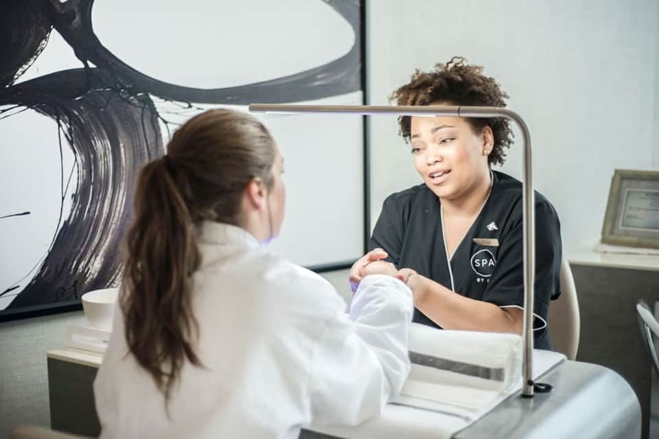 Spa staff member in black uniform assisting guest at reception desk