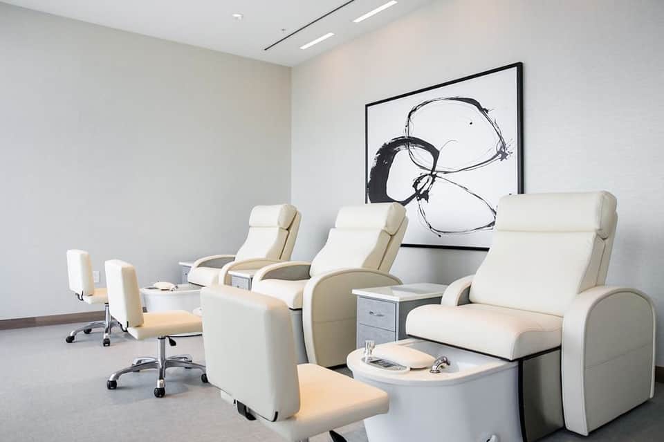 Spa relaxation room with cream-colored massage chairs arranged in a minimalist white interior
