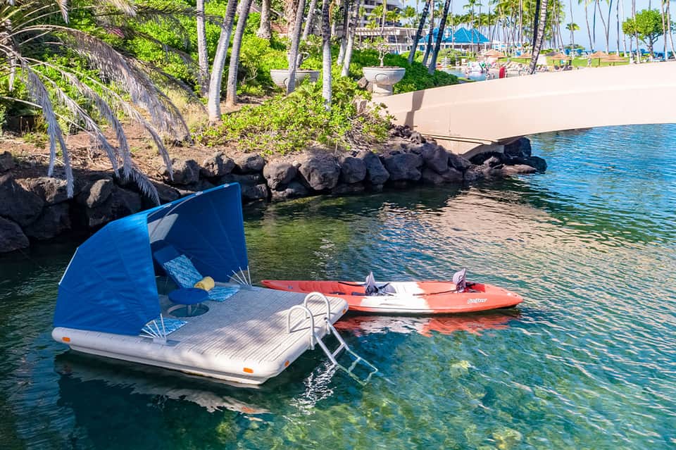 Kayak and paddleboard moored in clear blue water near sandy beach with palms