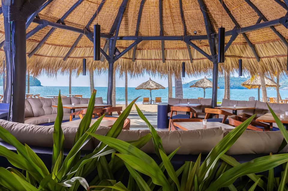 Beachfront restaurant pavilion with thatched roof overlooking turquoise ocean