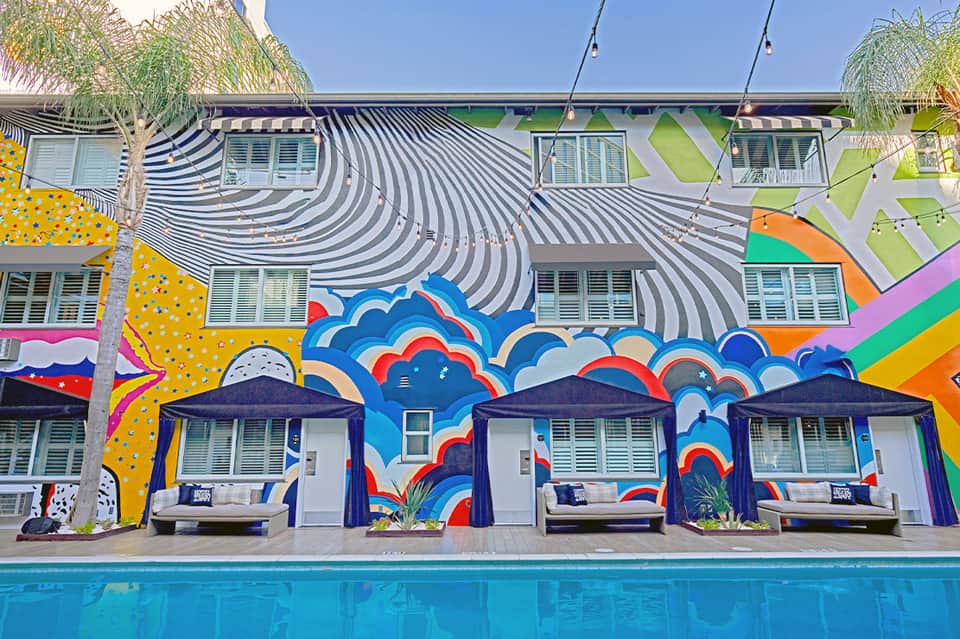 Colorful poolside cabanas with vibrant murals and striped beach umbrellas