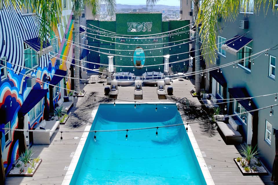 Rooftop pool deck with lounge chairs, colorful art installations, and city skyline views