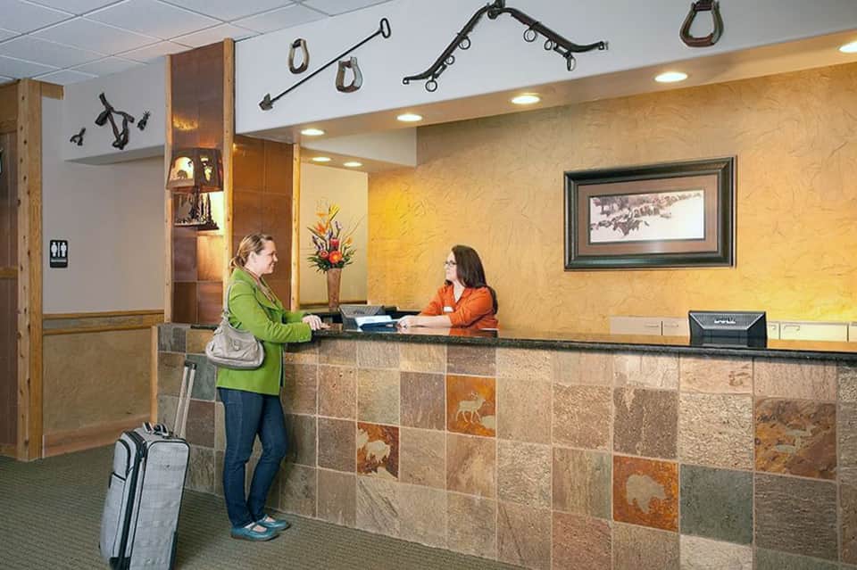 Hotel front desk with staff member checking in guest with rustic tile accent wall