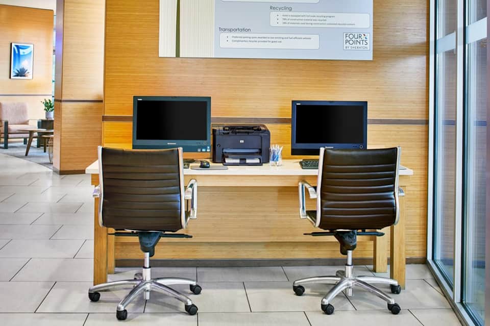 Hotel business center with two computer workstations and wooden wall paneling