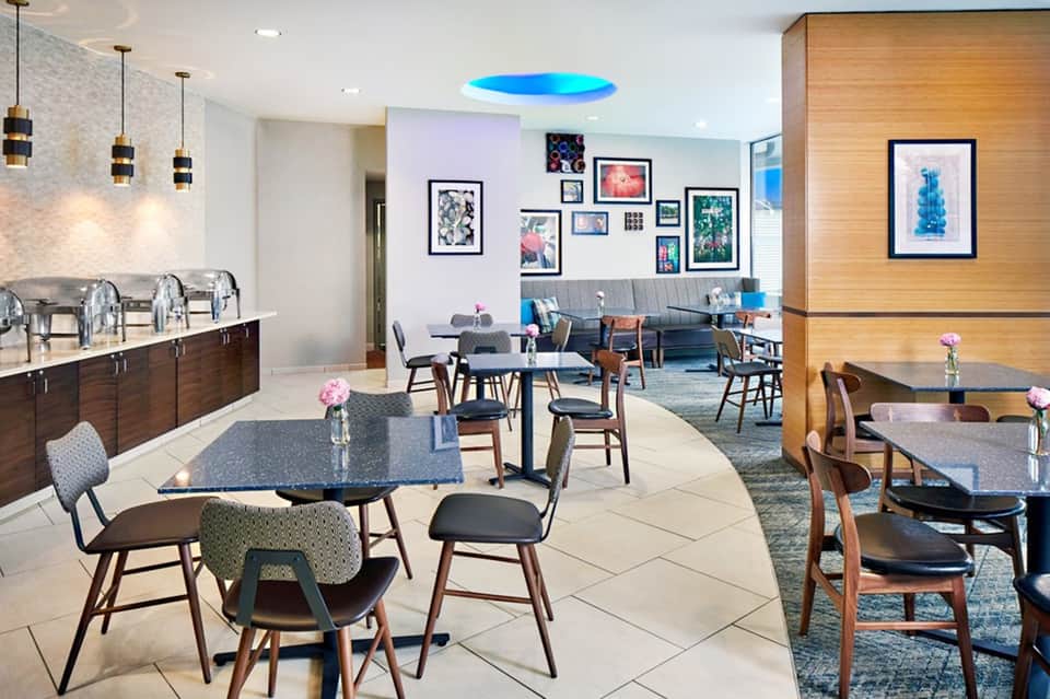 Contemporary cafe lounge with modern furniture, colorful wall art, and ambient blue ceiling light