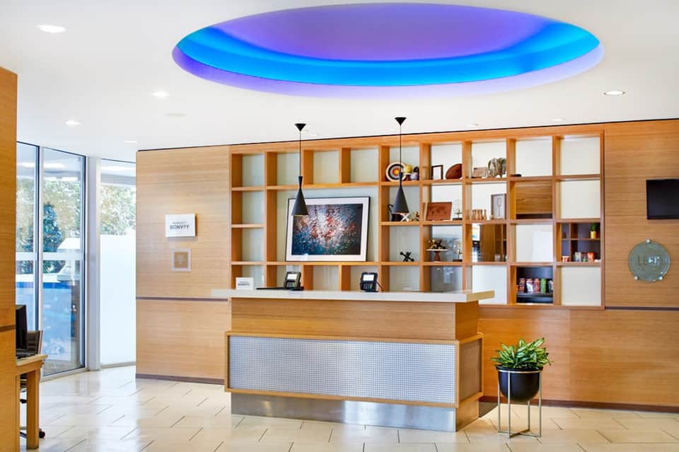 Modern hotel lobby with circular purple and blue ceiling, wooden wall shelving, and reception desk
