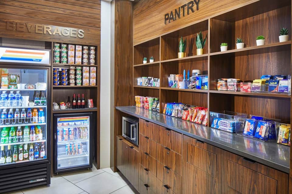 Resort beverage and pantry area with refrigerated drinks display and wooden shelving with snacks