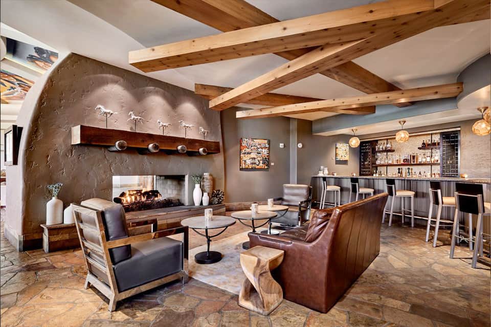 Modern resort lounge with fireplace, exposed wood beams, bar area, and contemporary furnishings