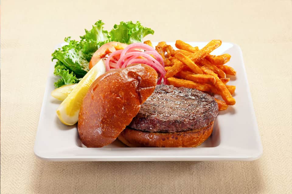 Steak burger with lobster tail, fries, lettuce, and lemon on white plate