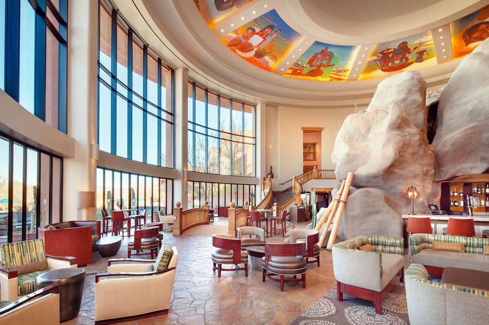 Modern resort lobby with high ceilings, decorative artwork, large windows, and contemporary furnishings