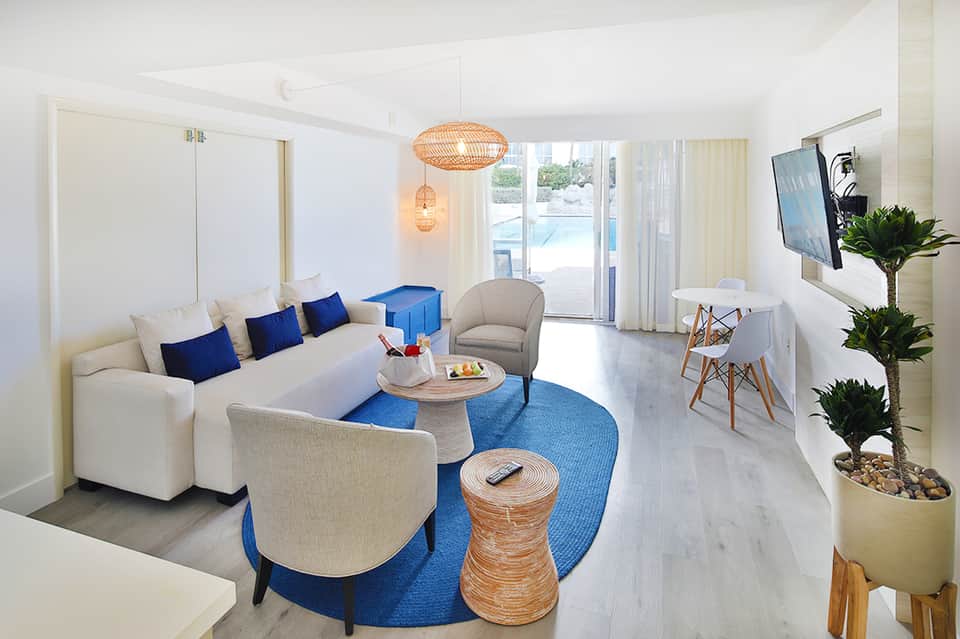 Modern resort suite with white sofa, blue accents, and direct beach access