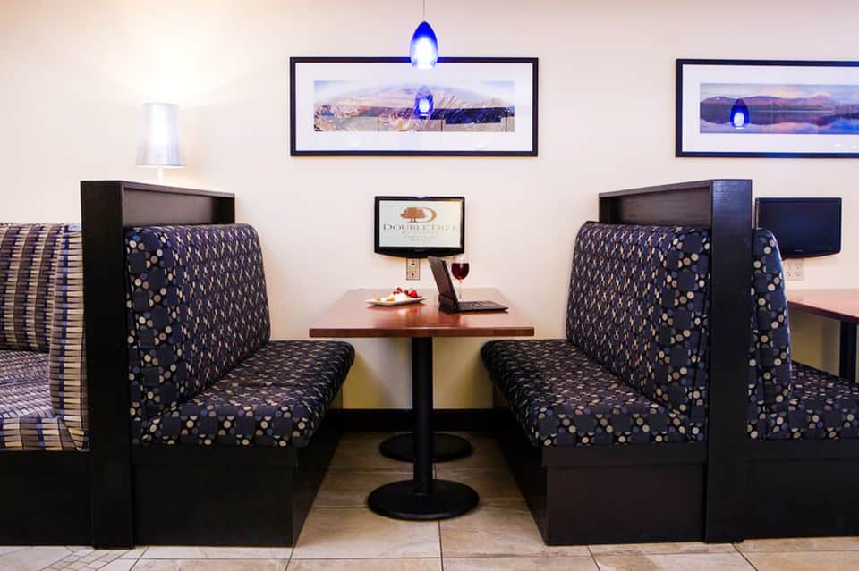 Hotel suite seating area with patterned upholstered booths and framed landscape artwork on walls