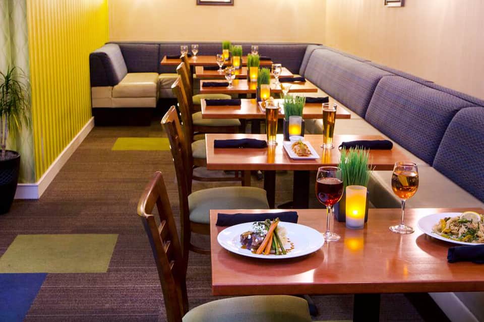 Fine dining restaurant interior with long tables, purple seating, and plated gourmet dishes