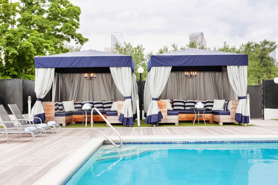 Luxury pool cabanas with navy and white striped cushions beside swimming pool with lounge chairs
