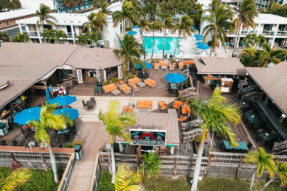 Aerial view of resort courtyard with pool, orange lounge chairs, and palm trees