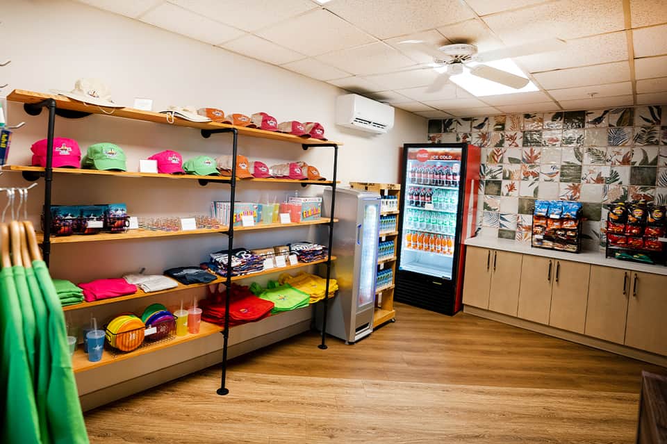 Resort gift shop interior with colorful merchandise, branded apparel, and beverage cooler