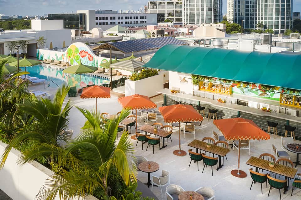 Rooftop pool deck with colorful umbrellas, lounge chairs, and city skyline views