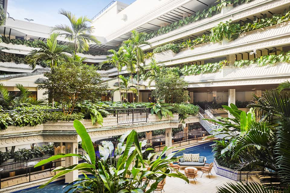 Luxurious multi-level courtyard with tropical plants, blue pool, and modern architectural design