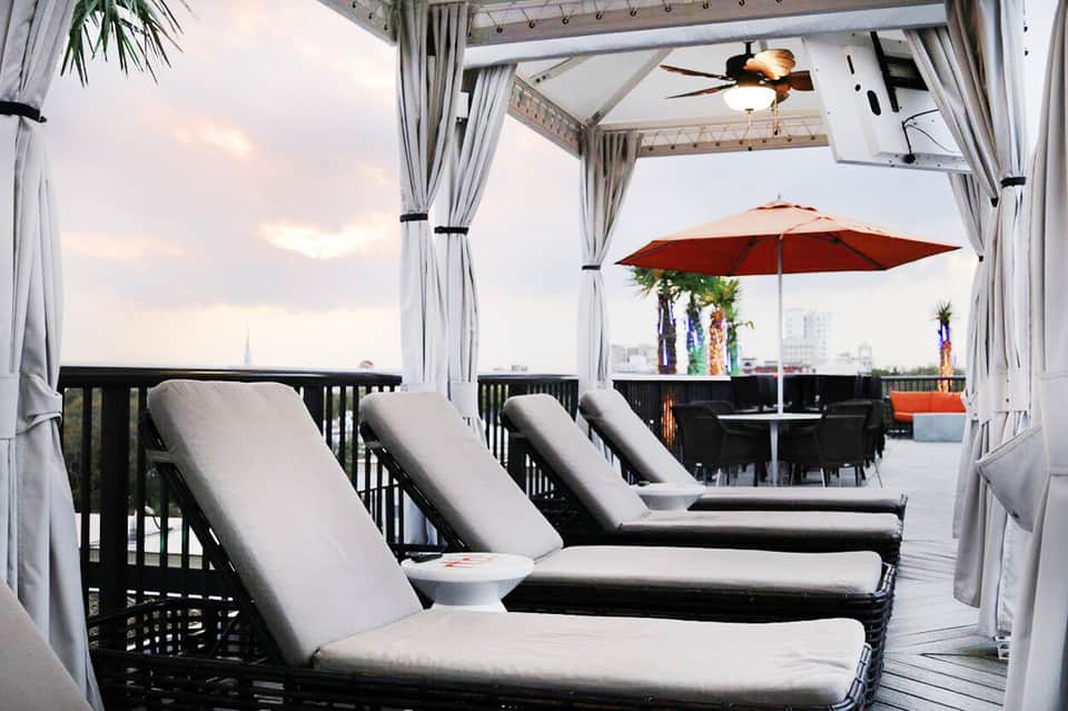 Modern rooftop lounge with daybed, curtains, umbrella, and city skyline view
