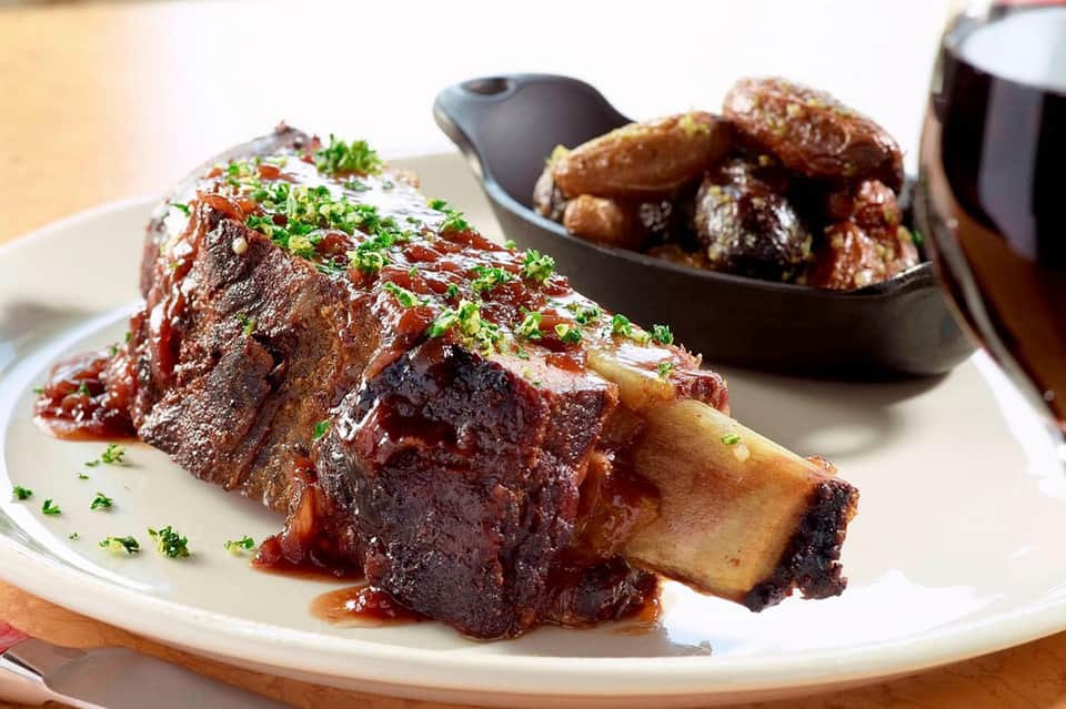 Plated braised short ribs with garnish and roasted potatoes at upscale restaurant