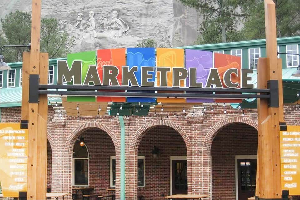 Colorful marketplace sign with arched brick building entrance and outdoor dining area