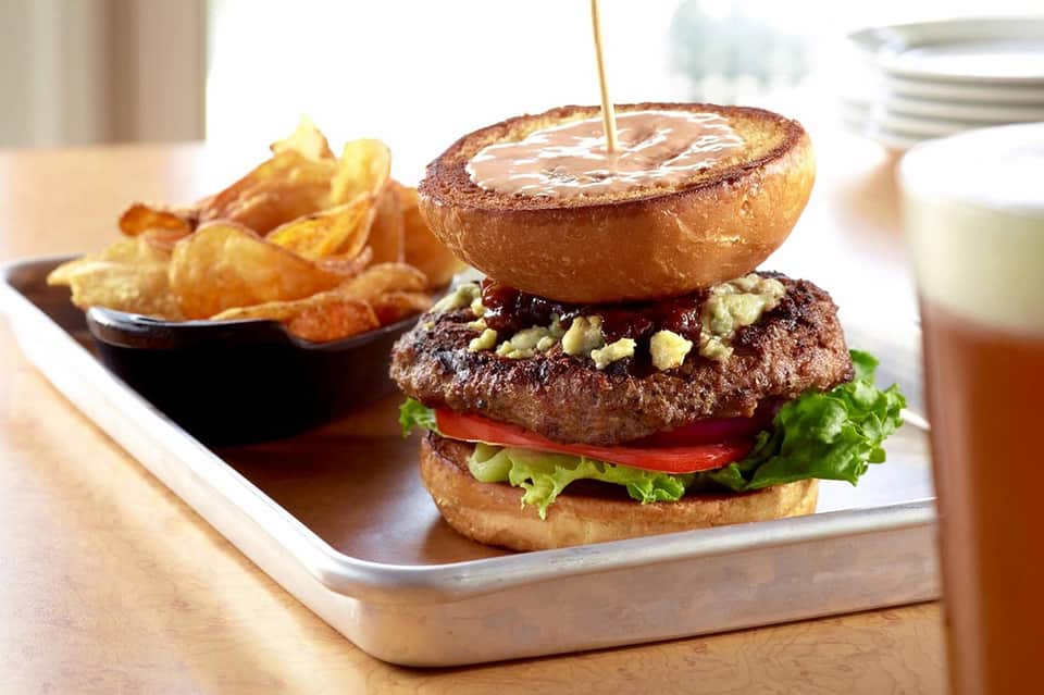Gourmet burger with fries and sauce on white plate at upscale dining establishment