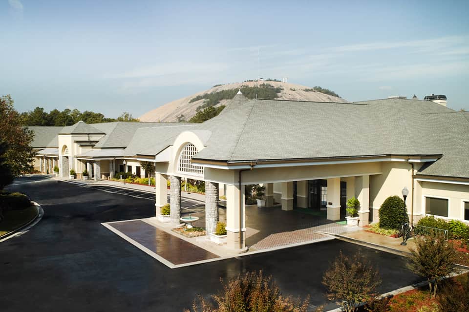 Modern cream-colored resort entrance with arched architecture and manicured landscaping
