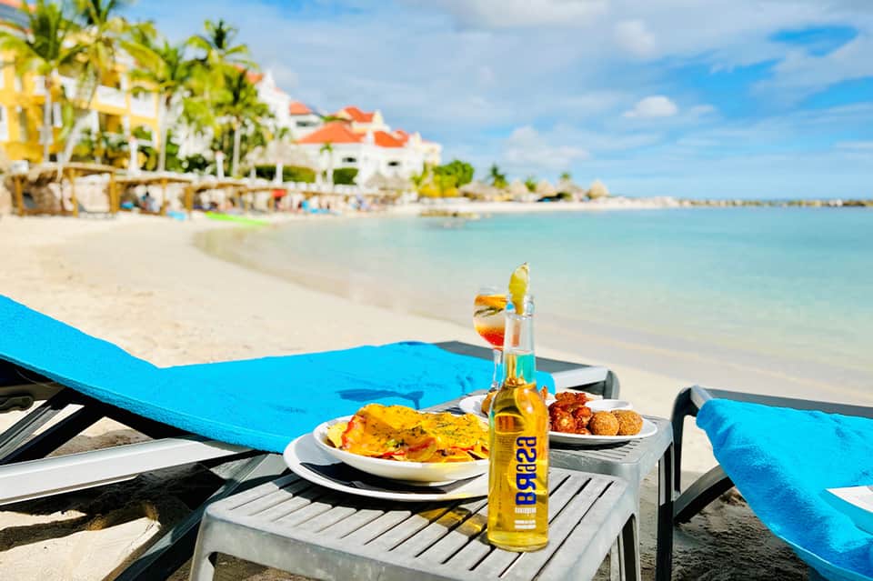 Beachfront dining with fresh fish meal and beverage on table overlooking tropical shoreline