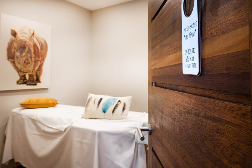 Spa massage room with do not disturb sign, treatment table, and decorative artwork