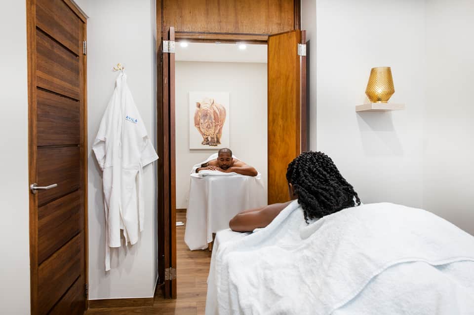Spa massage room with woman relaxing on bed and man in soaking tub